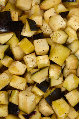 A macro, close-up, top-down view of freshly diced eggplants coated in olive oil, salt, and pepper, ready for roasting