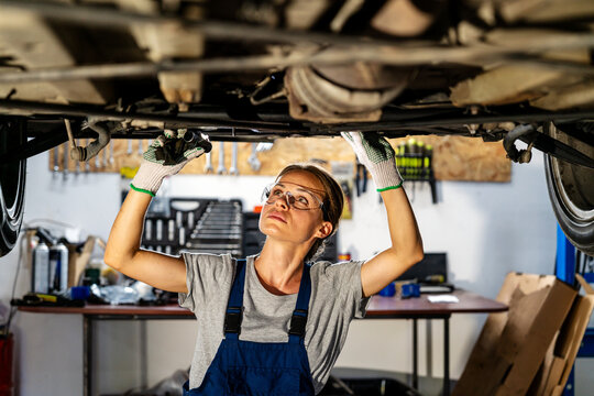 Female auto mechanic diagnostic vehicle in auto repair shop.