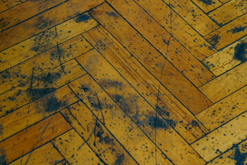 Wooden floor with herringbone pattern showing signs of wear and aging