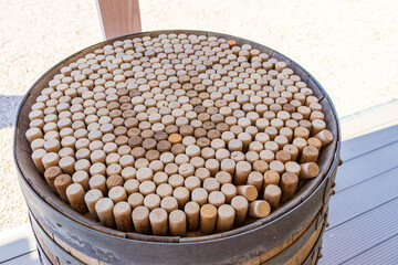 Naklejka premium Close-up of a wooden wine barrel filled with hundreds of corks, symbolizing wine culture, sustainability, and tradition. Captured in a sunny outdoor setting at a vineyard or winery, representing eco