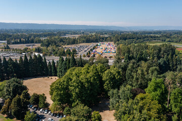 Aerial drone photo of a colorful outdoor play park and event area for kids, near Portland International Raceway and Interstate 5 in North Portland, with a huge busy parking lot, under blue sky