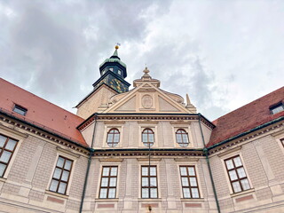 Fototapeta premium A view up at the various architectural styles of different eras of buildings in the historical part of Munich while walking along quiet, cozy streets on a cloudy rainy summer day.