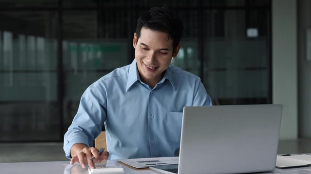 Professional businessman analyzing financial data, working efficiently on laptop and calculator at modern office desk, demonstrating corporate success and digital expertise