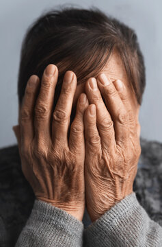 Depressed and frustrated senior woman with hands covering his face