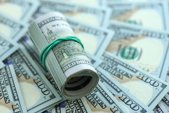 Roll of hundred dollar bills USD banknotes lies on big amount of united states money