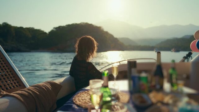 Romantic dinner on yacht, woman admiring view on seacoast from pleasure boat. Enjoying luxury life and solitude, lady traveling to unknown shores, sea cruise on yacht, unity of person and nature