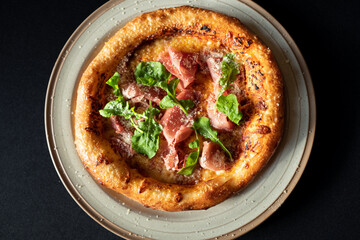 Gourmet Pizza Delight: An overhead shot showcases a freshly baked pizza, artfully adorned with prosciutto and fresh arugula, inviting the viewer to savor the moment.