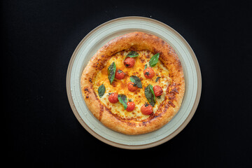 Golden Pizza Delight: A delectable, mouth-watering pizza, adorned with cherry tomatoes and basil leaves, takes center stage on a beautifully crafted plate.