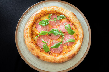 Gourmet Pizza with Salami: A close-up shot showcases a freshly baked pizza topped with delicious salami slices and fresh arugula, served on a rustic plate, evoking a sense of indulgence.