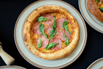 Pizza on the Plate: A mouthwatering pizza, adorned with succulent salami and fresh green arugula, rests appetizingly on a ceramic plate, inviting viewers to savor its flavors.