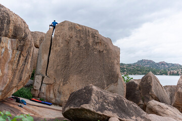 Rock climber on top of a boulder about to top out with a beautiful view.