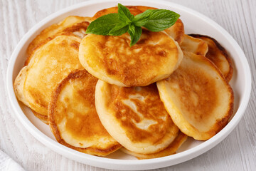Delicious golden pancakes served on a white plate with fresh mint leaves on top