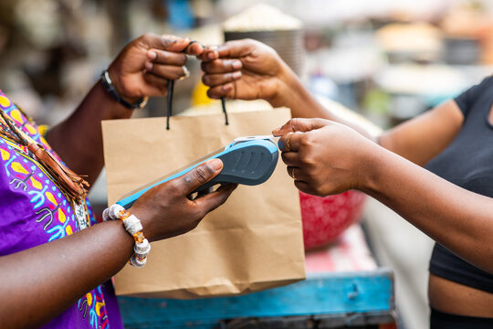Contactless payment in Africa. A customer makes a successful transaction via mobile point of sale, POS terminal at an outdoor local traditional market.