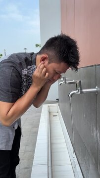 Muslim man wiping head with wet hands during ablution ritual before Islamic prayer