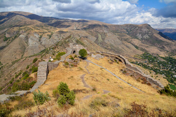 Walls and arches of an old castle. Entrance to the fortress. Old fortress architecture. Castle in the mountains. Rocky high mountains and a castle. Smbataberd Fortress in Armenia