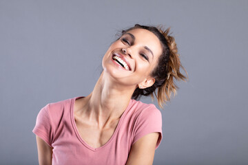 Close-up portrait of a woman beaming with happiness and joy, on grey