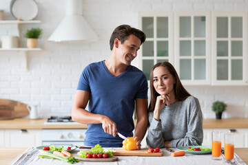 Young man and woman are jointly preparing wholesome vegetable-based meals in the kitchen, enjoying quality time together and focusing on balanced eating