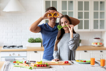 Couple in the kitchen preparing a dish from healthy vegetables, chatting happily, balanced nutrition.