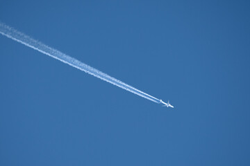 twin engined jet liner aircraft with contrails, in flight at high altitude, clear blue sky