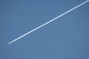 twin engined jet liner aircraft with contrails, in flight at high altitude, clear blue sky