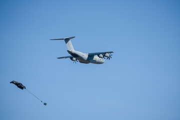 RAF Airbus C.1 A400M Atlas military transport aircraft in flight on a low-level cargo drop run, CDS parachute deploying, blue sky