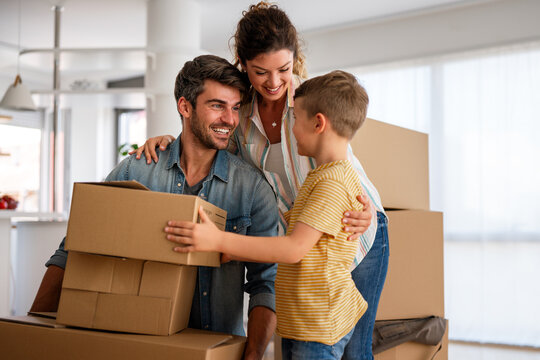 Smiling man and woman enjoy unpacking with child moving to own home. Rent, mortgage concept