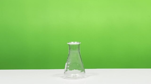 150 ml Erlenmeyer flask on white table with green background, laboratory glassware footage for science and education use