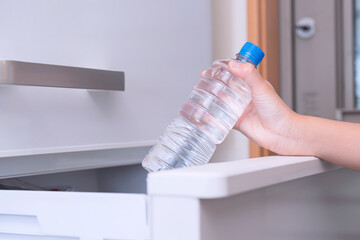 take a water plastic bottle from the refrigerator. 冷蔵庫から水の入ったペットボトルを取る。