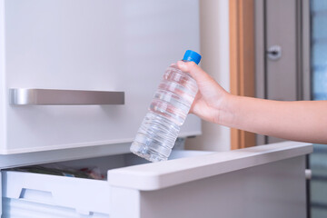 take a water plastic bottle from the refrigerator. 冷蔵庫から水の入ったペットボトルを取る。