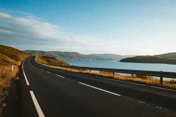Fototapeta premium A scenic road with clear sky and lake view in the distance