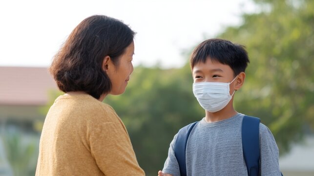 Woman and boy wearing masks outdoors during daytime.