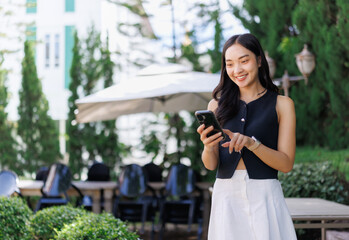 Smiling businesswoman using smartphone in outdoor cafe