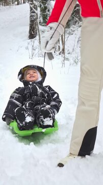 Grandmother pulling child on sled in snowy Finland, enjoying winter family lifestyle outdoors. Warm clothing, joy, love, and seasonal holiday atmosphere in bright daylight.