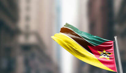 Mozambique national flag waving on street. A beautiful with mast with blur buildings. Mozambique...