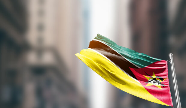 Mozambique national flag waving on street. A beautiful with mast with blur buildings. Mozambique national flag for independence day.