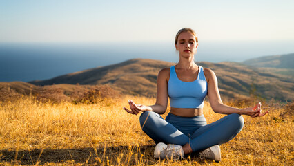 Peaceful woman meditating outdoors in mountains at golden hour, sitting in lotus yoga pose with sea at sunrise background with closed eyes in sportswear, full length front view