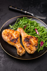 Deliciously grilled chicken legs drumsticks, featuring a crispy skin and juicy meat, a must have for any outdoor feast. black background. top view