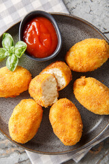Close-up of Spanish chicken croquettes with ketchup in a plate on a table. Vertical top view from above
