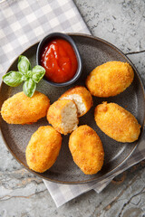 Chicken Croquettes Croquetas de Pollo with ketchup close-up in a plate on the table. Vertical top view from above