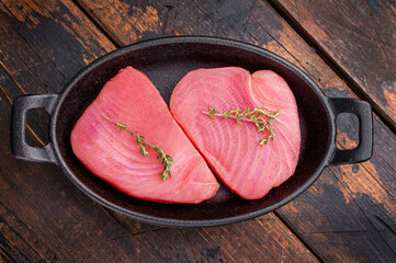 Vibrant raw tuna steak, showcasing its deep red hue, an essential ingredient for sushi enthusiasts and seafood connoisseurs. wooden background. top view