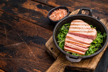 Tender grilled tuna steak on a bed of greens, an exquisite blend of flavors that delights the palate.  wooden background. top view
