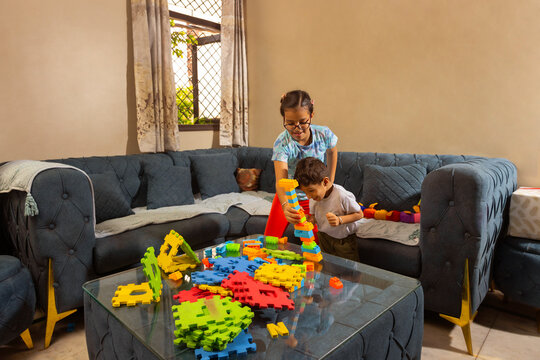 Two kids enjoying playtime at home, building towers and shapes with colorful blocks in the living room