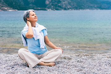 Mature Woman Enjoying Relaxation on Pebble Beach by Sea, Embracing Tranquility and Nature