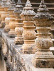 Obraz premium A row of stone pillars with a clock in the background