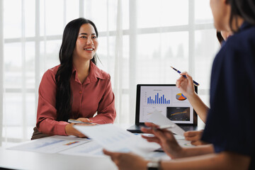 Businesswomen discussing charts and graphs on laptop during meeting