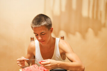 Young Man Chewing a Bite of Watermelon at the Dining Table.