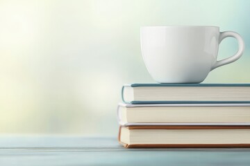 A minimalist image featuring a white cup resting on a stack of books, set against a soft, blurred background.
