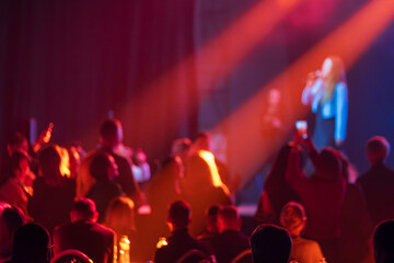 Audience enjoys live performance on stage illuminated by striking red lighting creating dynamic atmosphere