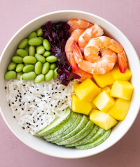 Hawaiian poke bowl with rice, shrimp, red cabbage, radish, edamame, and mango. Healthy eating. Diet.