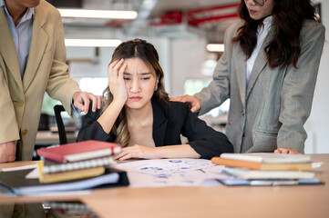 Upset asian businesswoman resting head on one hand while getting comfort at working table in office.